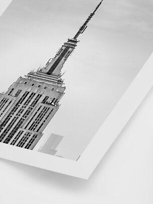 Black-and-white poster of the Empire State Building spire viewed from below at an angle