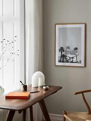 Indrammet sort-hvid Las Vegas-plakat over et træskrivebord i et lyst, minimalistisk rum