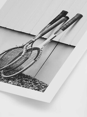 Affiche noir et blanc montrant deux raquettes de tennis vintage contre un mur