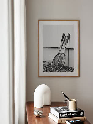 Photo encadrée noir et blanc de raquettes de tennis au-dessus d'une table en bois décorée