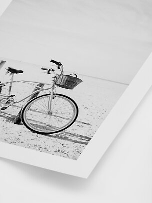 Sort-hvid vægkunst med cykel med kurv på en sandstrand