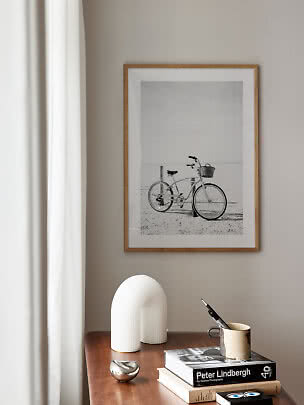 Indrammet sort-hvid cykelfoto over et træbord med bøger, kop og hvide dekorationer