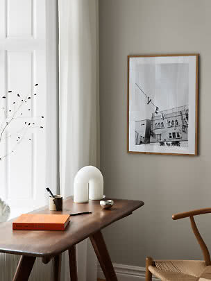 Lámina en blanco y negro enmarcada en pared beige sobre mesa de madera en sala minimalista