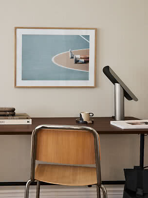 Schreibtisch mit Stuhl, Lampe und gerahmtem Kunstdruck an der Wand
