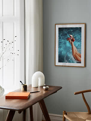 Framed photo art of legs in red heels above blue pool water on a gray wall