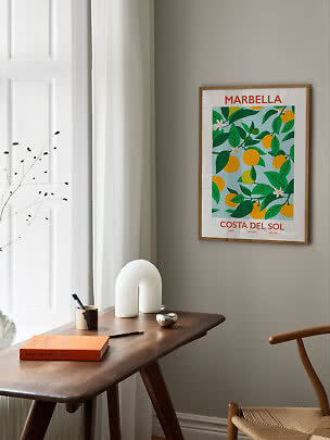 Framed Marbella citrus poster above a wooden desk in a bright, minimalist room