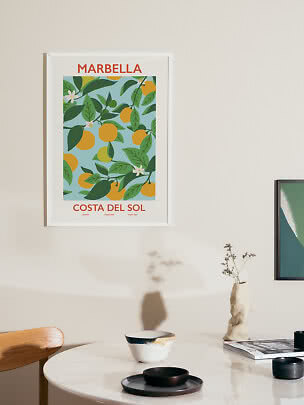 Framed Marbella citrus poster hanging above a round table in a bright room