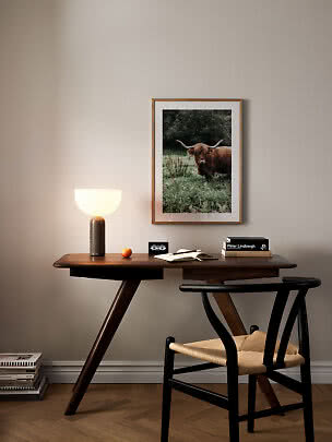Photo encadrée d’une vache Highland au-dessus d’un bureau en bois avec lampe et chaise noire