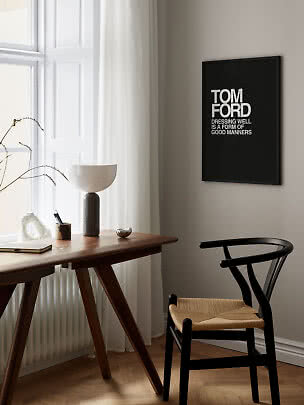 Poster tipografico Tom Ford con cornice nera sopra una scrivania in una stanza luminosa