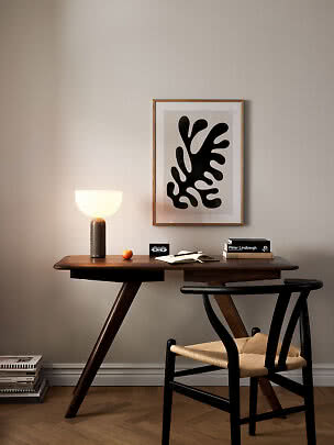Escritorio de madera oscura con silla, lámpara de mesa, libros y arte abstracto
