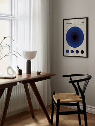 Gerahmtes Bauhaus-1919-Poster mit blauen Kreisen an beigefarbener Wand über einem Schreibtisch