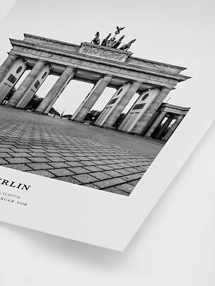 Czarno-biały plakat z Bramą Brandenburską w Berlinie, sfotografowaną z niskiej perspektywy