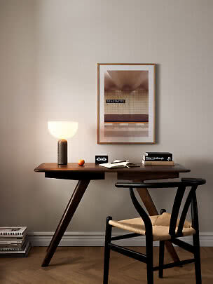 Dunkler Holzschreibtisch mit schwarzem Stuhl, Tischlampe, Büchern und gerahmtem Poster an beiger Wand