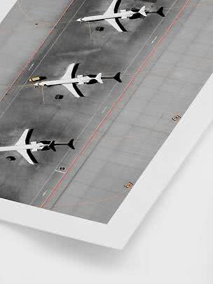 Luftfoto af tre fly parkeret på en grå lufthavnsforplads med markeringer