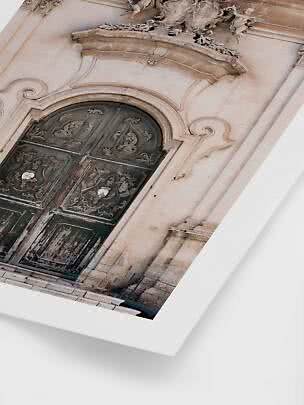 Primer plano de una antigua puerta de madera ornamentada en fachada de piedra clara con detalles barrocos