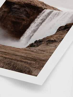Indrammet fotoprint af stort vandfald over mørke klipper i brunt landskab