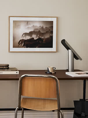 Skrivebord med stol, lampe og indrammet hestefoto på væggen