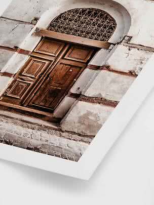 Photo print of an old wooden door with arched iron grille in a weathered stone wall