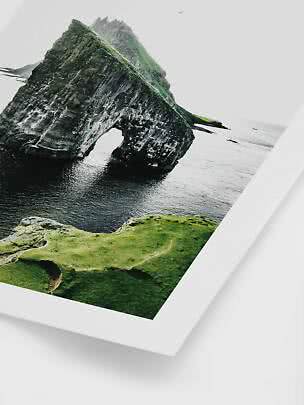 Photo of a green rock formation with a natural arch over the sea