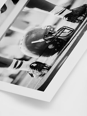 Foto in bianco e nero di un casco da football americano e mani di giocatori sul campo
