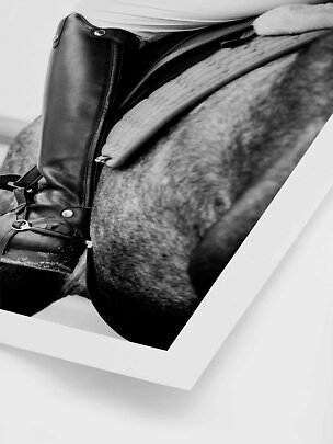 Primo piano in bianco e nero di stivale da equitazione e sella su un cavallo