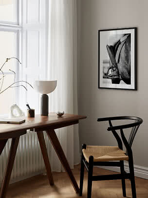 Elegante angolo studio con scrivania in legno, sedia nera, lampada e foto in bianco e nero