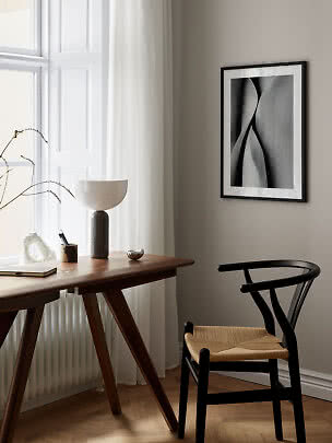 Stampa astratta con cornice nera su parete beige sopra scrivania e sedia nera