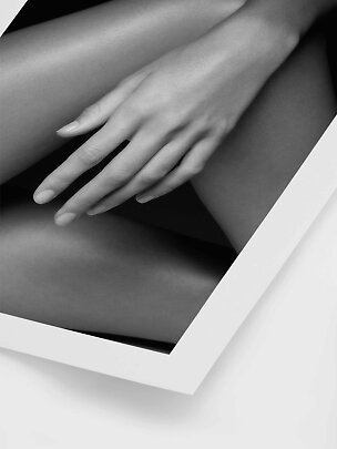 Black-and-white close-up of a hand resting on a bent leg.