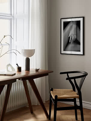 Black framed black-and-white art print of a hand on a wall in a minimalist interior