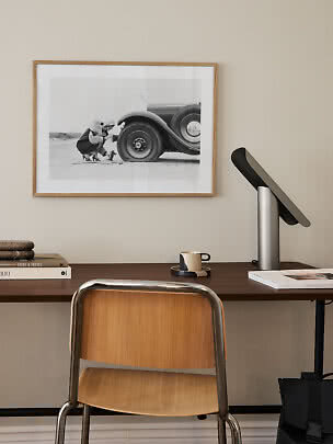 Skrivebord med træstol, sort lampe og indrammet sort-hvid foto på væggen