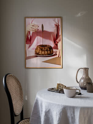 Framed kitchen poster of a person in pink pouring icing over a bundt cake