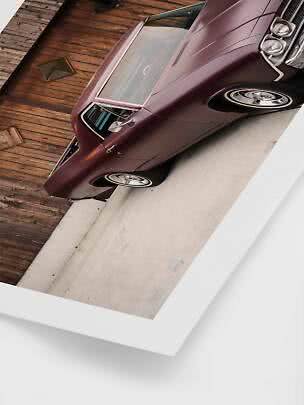 Poster of a vintage burgundy car parked by a wooden wall, viewed at an angle from above