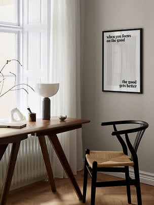Minimalistische werkplek met houten bureau, zwarte stoel en ingelijste typografieposter