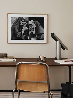 Skrivebord med træstol, lampe og indrammet sort-hvidt foto på væggen
