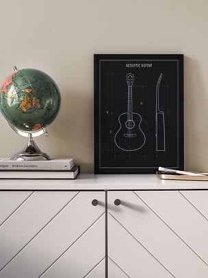 Sort indrammet plakat med akustisk guitar-tegning på hvid kommode ved siden af en globus