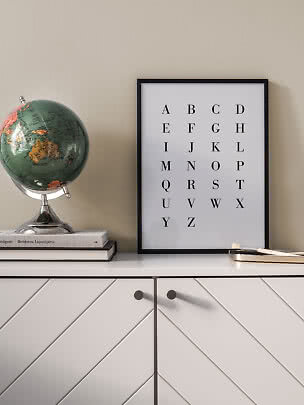 Framed alphabet print on a cabinet beside a globe and books