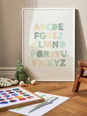 Framed pastel ABC poster leaning against the wall in a child's room
