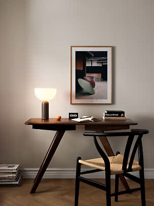 Bureau en bois foncé avec lampe allumée, chaise et photo encadrée au mur