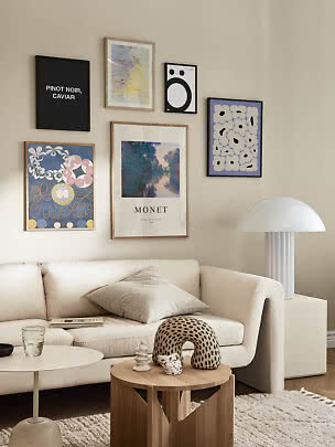 Bright living room with gallery wall above white sofa, round wood table and white lamp