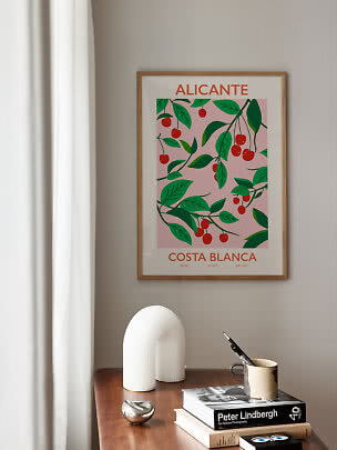 Poster Alicante incorniciato con ciliegie sopra un tavolo in legno con libri e tazza
