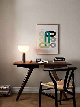 Schreibtisch mit leuchtender Tischlampe, Buch, Stuhl und gerahmtem Bauhaus-Poster an der Wand
