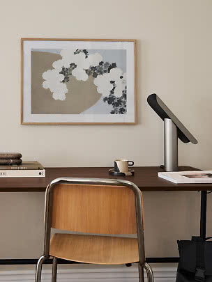 Home workspace with wooden chair, desk, lamp, and framed abstract wall art