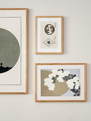Three art prints in light wood frames hanging on a white wall.