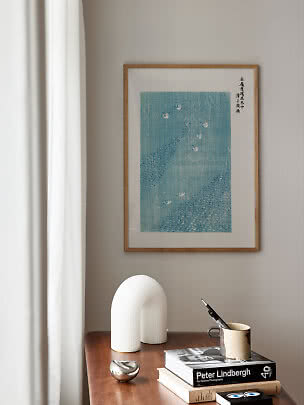 Stampa d’arte blu incorniciata con uccelli sopra un tavolo in legno con libri e oggetti decorativi