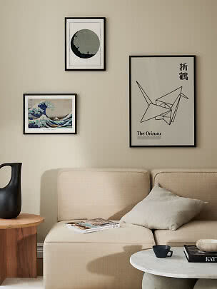 Tre inramade posters ovanför en beige soffa i ett modernt vardagsrum