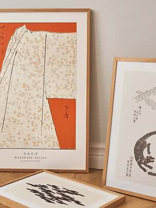 Trois affiches d’art en cadres bois clair contre un mur, avec motifs japonais orange et noirs