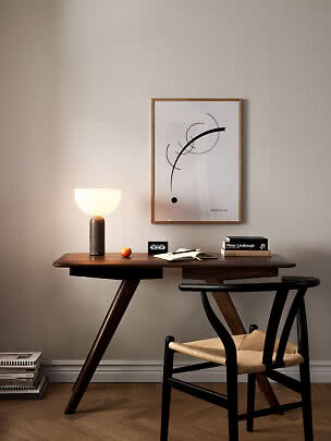 Træskrivebord med lysende bordlampe, stol, bøger og abstrakt plakat på væggen
