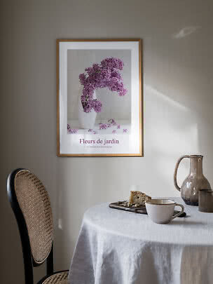 Gerahmtes Blumenposter mit violettem Flieder in weißer Vase über einem gedeckten Tisch