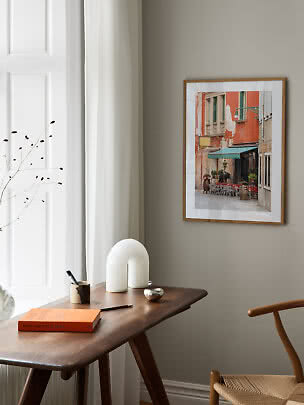 Foto enmarcada de una fachada de café con toldo verde sobre mesa de madera