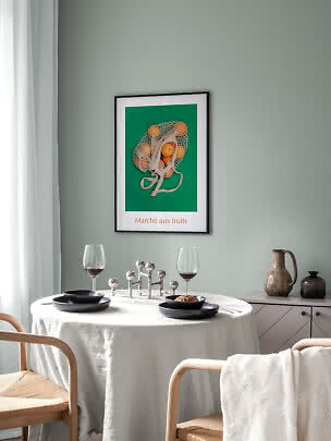 Essecke mit rundem Tisch, schwarzen Tellern, Weingläsern und Obstposter an grüner Wand.
